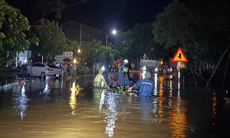 Người dân dùng bè chở xe máy qua đoạn ngập sâu trên Quốc lộ 12B